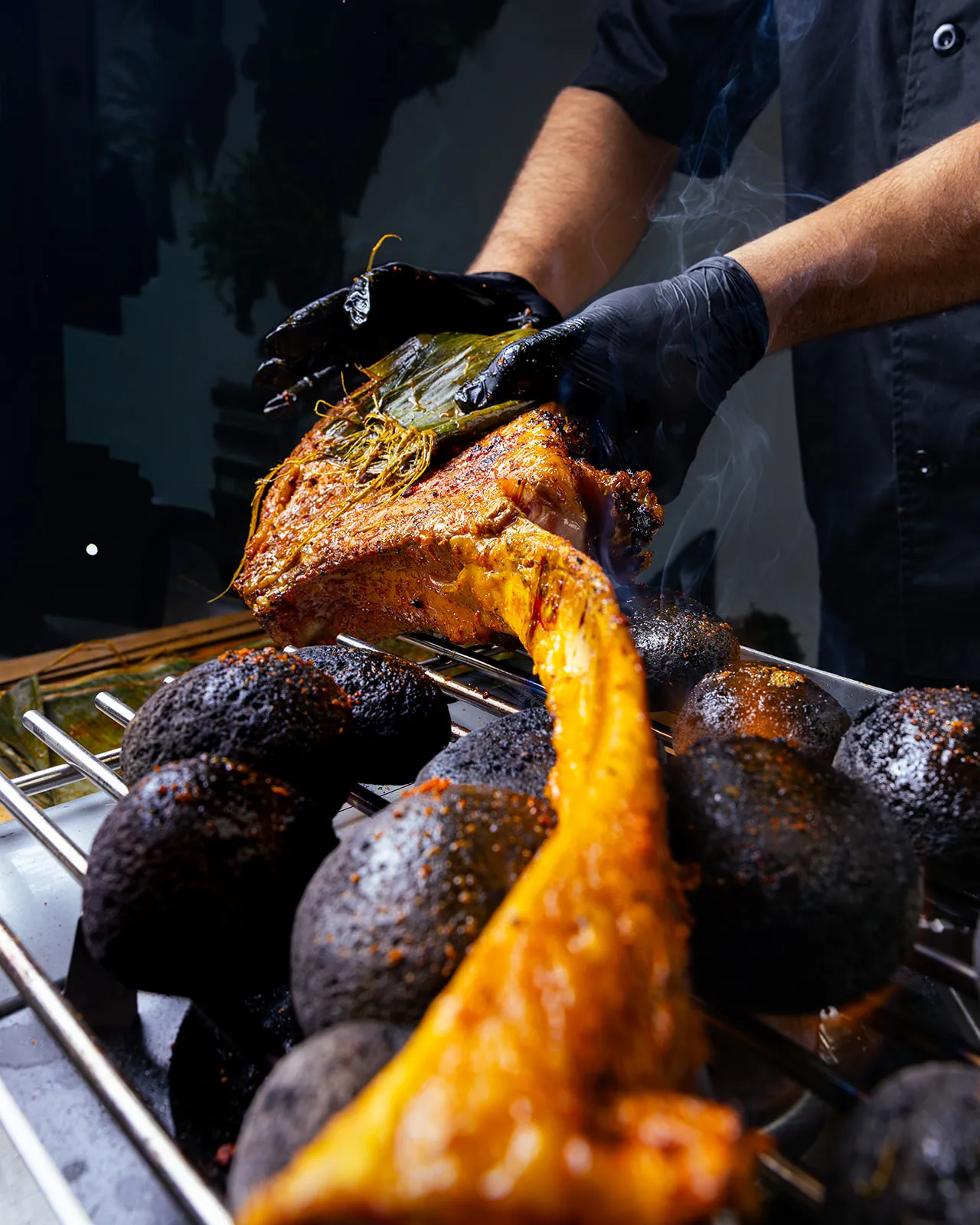 Chef lifting a tomahawk steak off charcoal · juices cascading · Cocina Maya